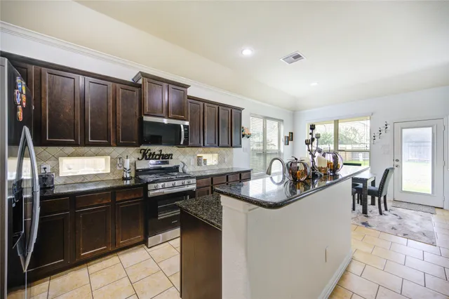 a kitchen with kitchen island granite countertop a stove sink cabinets and refrigerator