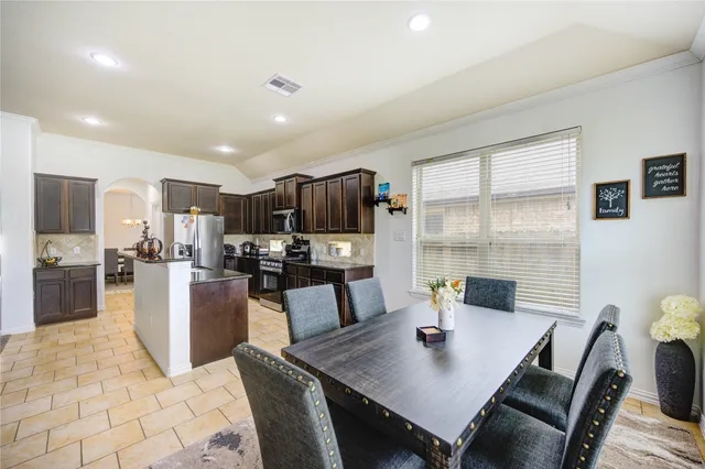 a view of a dining room with furniture a kitchen and chandelier