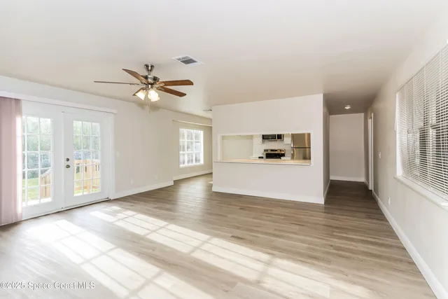 a view of an empty room with window and wooden floor