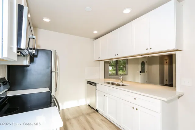 a kitchen with a sink a microwave a refrigerator and cabinets