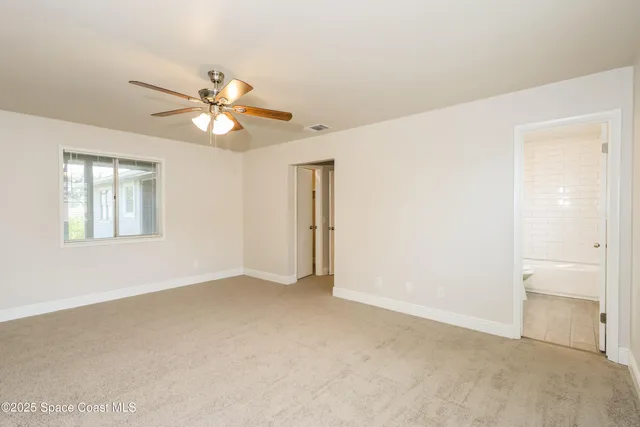 an empty room with fan and windows