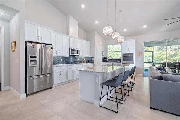 a kitchen with granite countertop stainless steel appliances a refrigerator a stove a sink a dining table and chairs