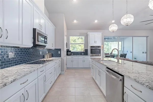 a large kitchen with granite countertop a sink and dishwasher stove top oven with wooden floor