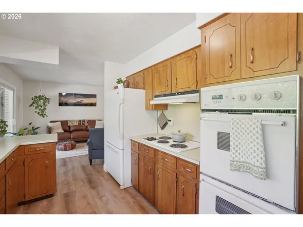 a kitchen with stainless steel appliances granite countertop a stove a refrigerator a sink dishwasher and white cabinets with wooden floor
