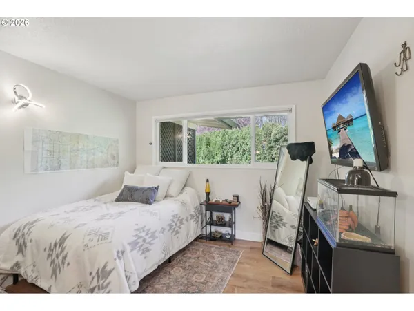a bedroom with a bed a flat screen tv and a large window