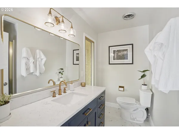 a bathroom with a granite countertop sink mirror vanity and toilet