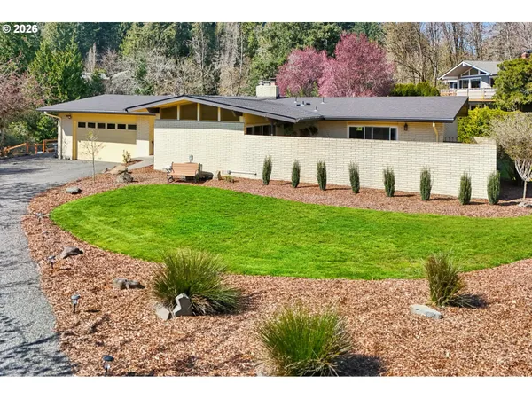 a white house with a big yard and large trees