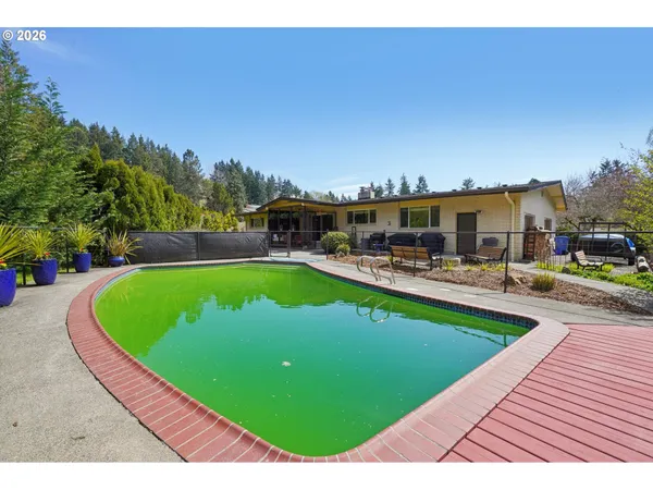 a view of a swimming pool with lawn chairs and a big yard