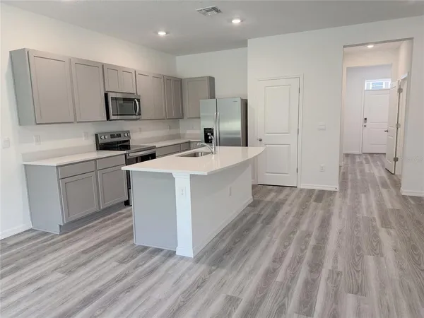 a kitchen with a sink a microwave a refrigerator and cabinets