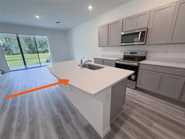 a large kitchen with stainless steel appliances a large counter top a stove and a refrigerator