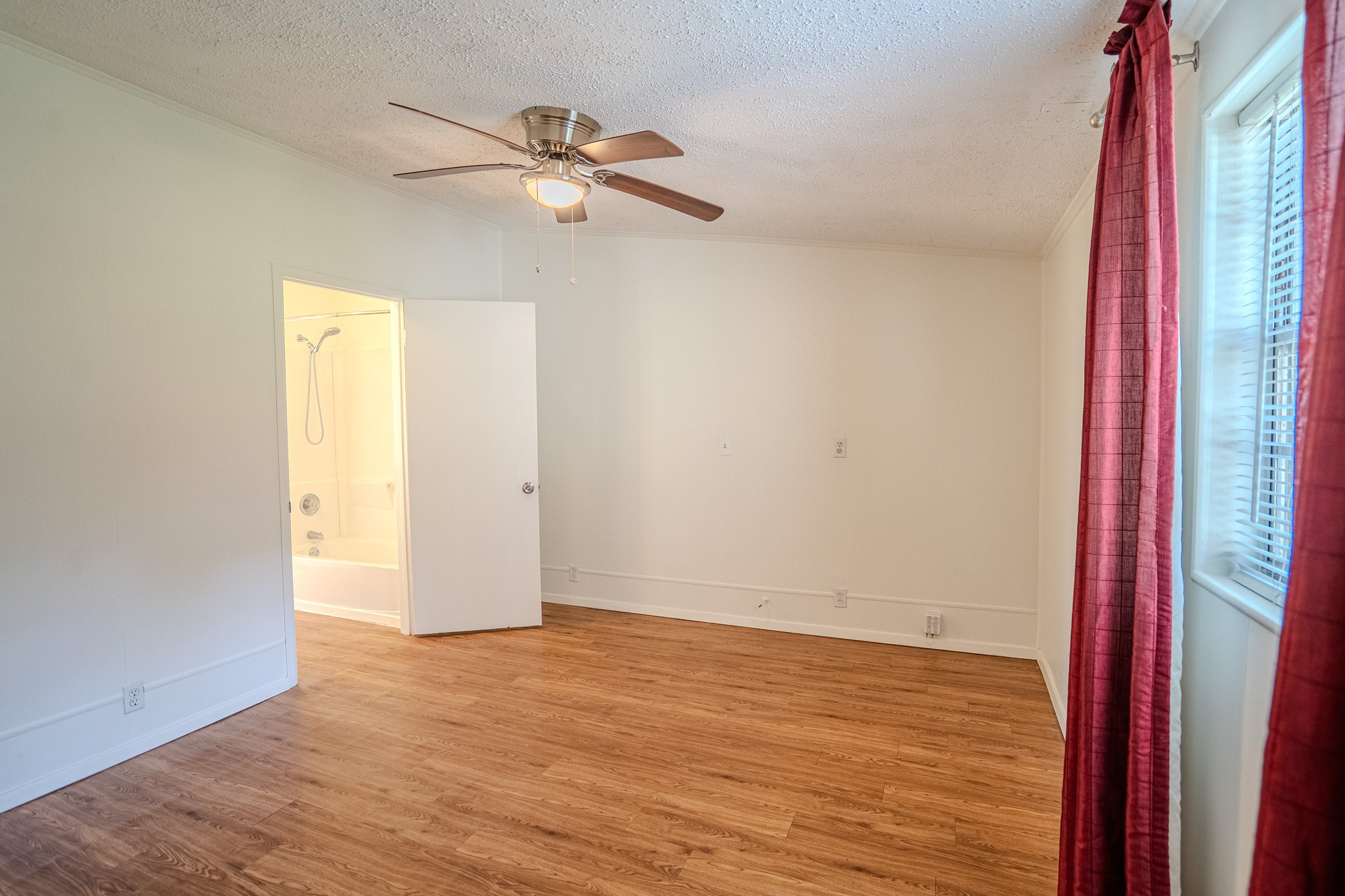 16013 Edwards Drive Austin, TX 78734 - Photo 17 of 18 Laminate flooring and a modern ceiling fan elevate this tranquil room, offering a seamless transition to the adjoining bathroom.