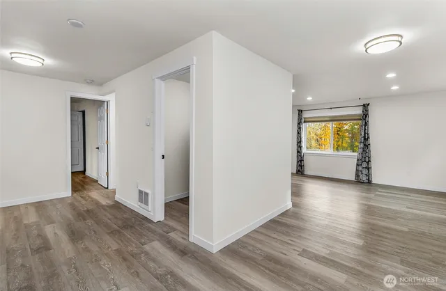 a view of an empty room with window and wooden floor