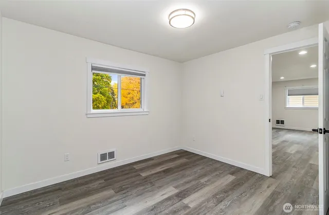 an empty room with a window and wooden floor
