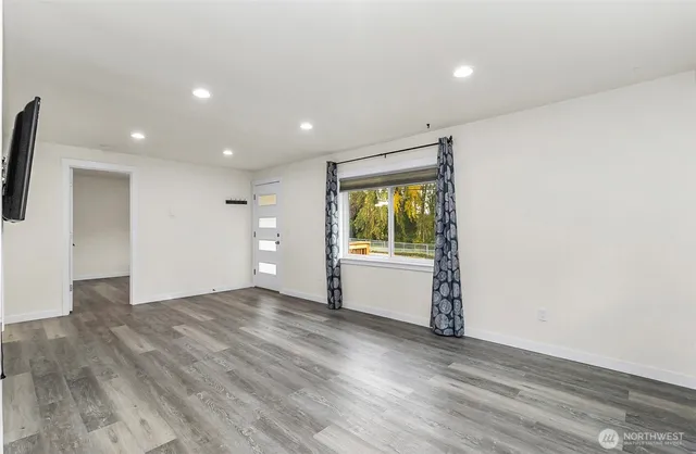 an empty room with wooden floor and windows