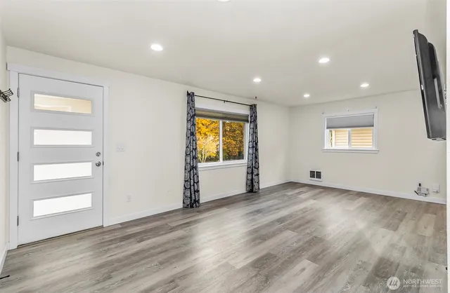 an empty room with wooden floor and windows