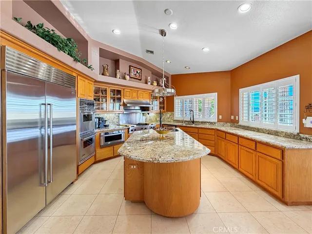 a large kitchen with stainless steel appliances granite countertop a large counter top and a refrigerator