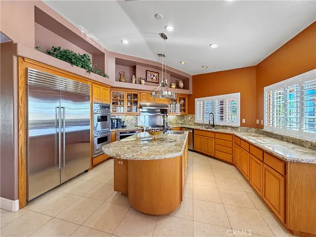a large kitchen with stainless steel appliances granite countertop a large counter top and a refrigerator