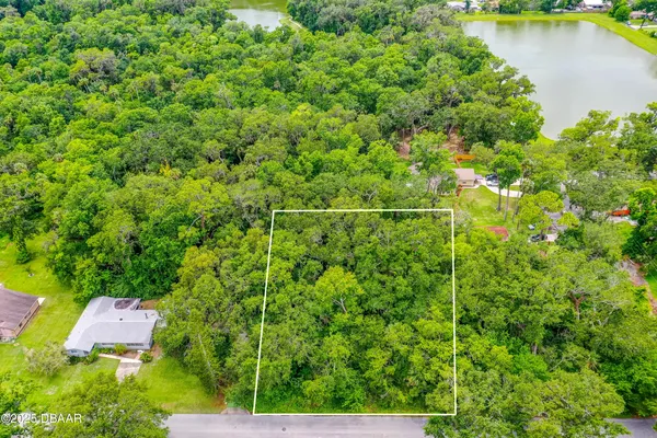 an aerial view of residential house with outdoor space and trees all around