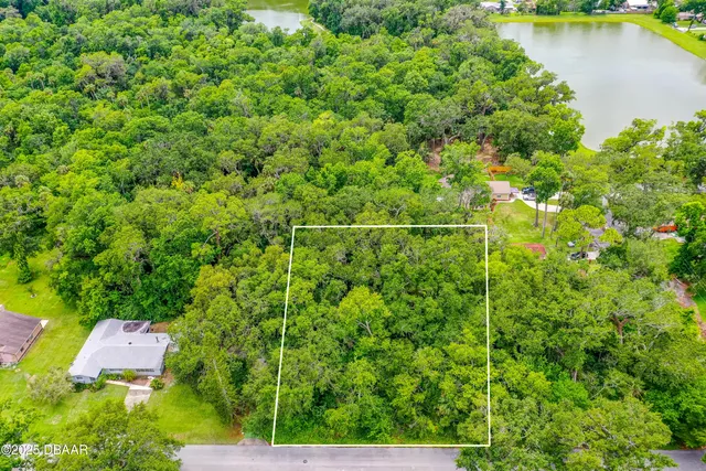 an aerial view of residential house with outdoor space and trees all around