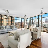 a living room with furniture large windows and wooden floor