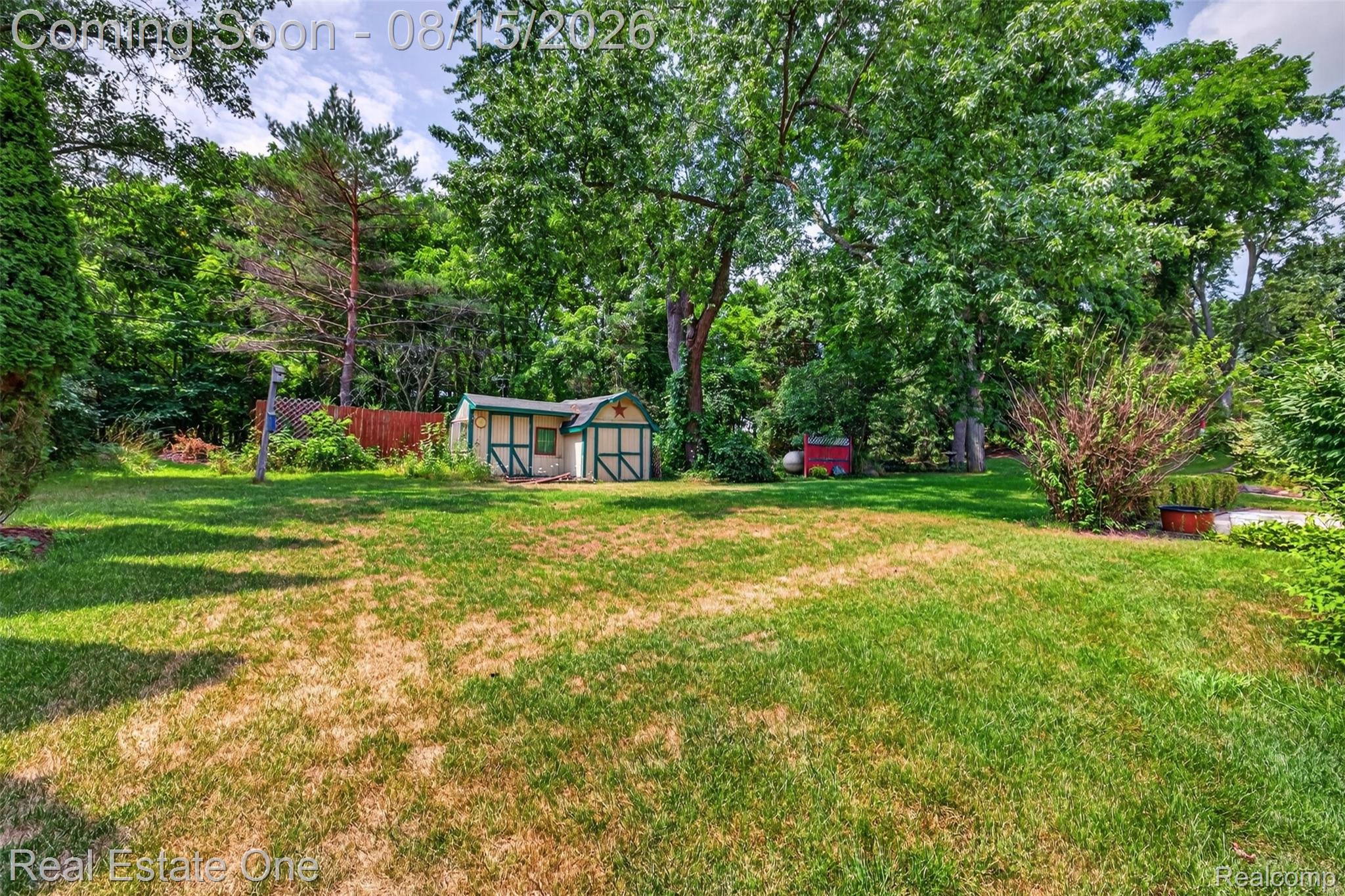 454 South Baldwin Road Oxford, MI 48371 - Photo 42 of 64 Spacious lawn area framed by mature trees, featuring a decorative storage shed with a red star accent