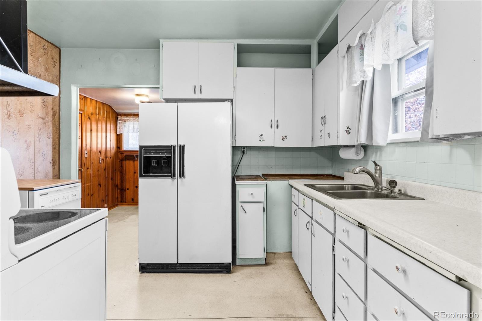 5919 South Bemis Street Littleton, CO 80120 - Photo 17 of 43 a kitchen with granite countertop white cabinets and refrigerator