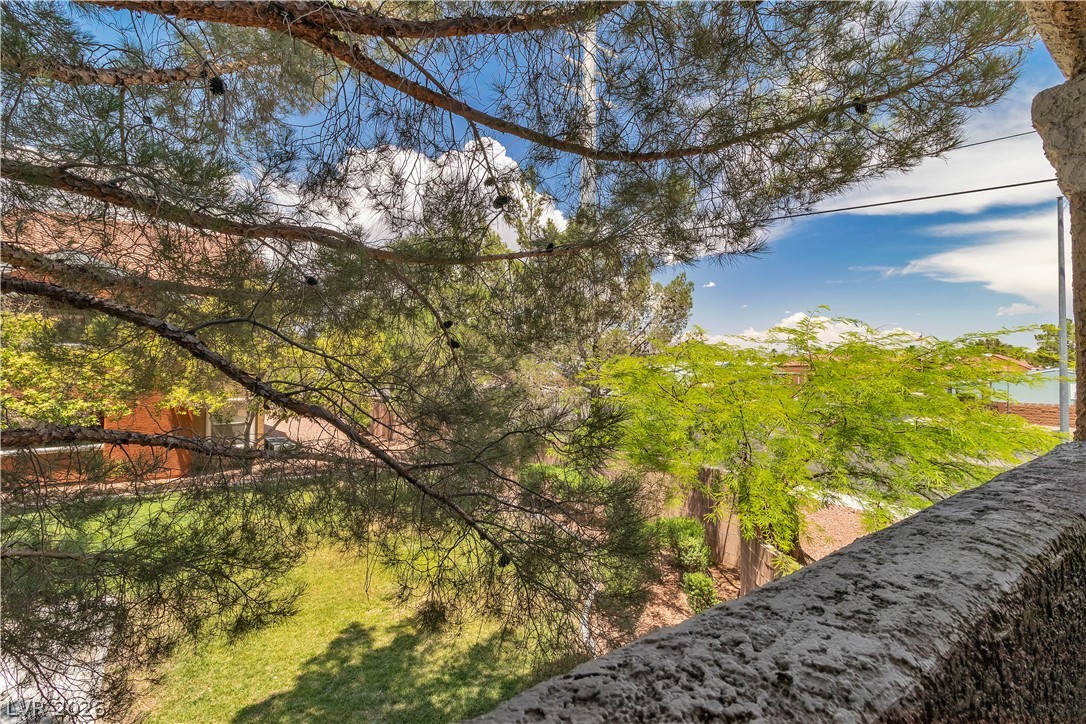 8101 West Flamingo Road, Unit 2001 Las Vegas, NV 89147 - Photo 17 of 28 A tranquil outdoor view from a balcony, showcasing vibrant trees and a manicured green space under a clear sky.