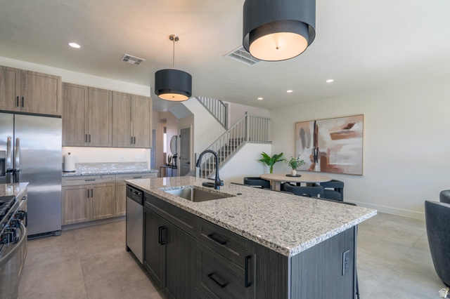 2972 West 570 North Hurricane, UT 84737 - Photo 37 of 104 Kitchen featuring light stone counters, stainless steel appliances, a center island with sink, and hanging light fixtures