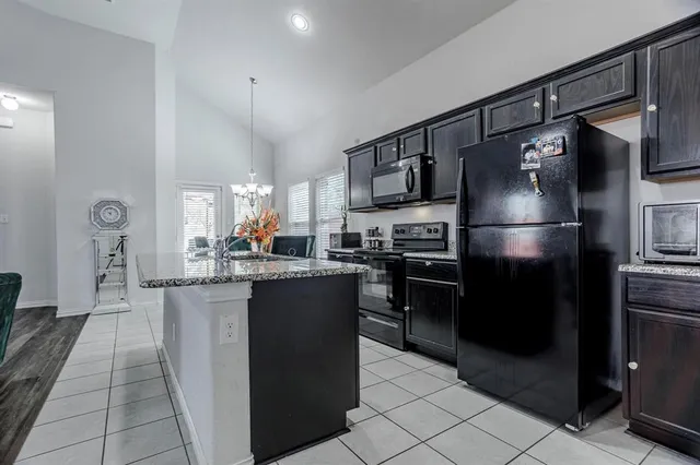 a kitchen with stainless steel appliances granite countertop a refrigerator a stove a sink and a microwave