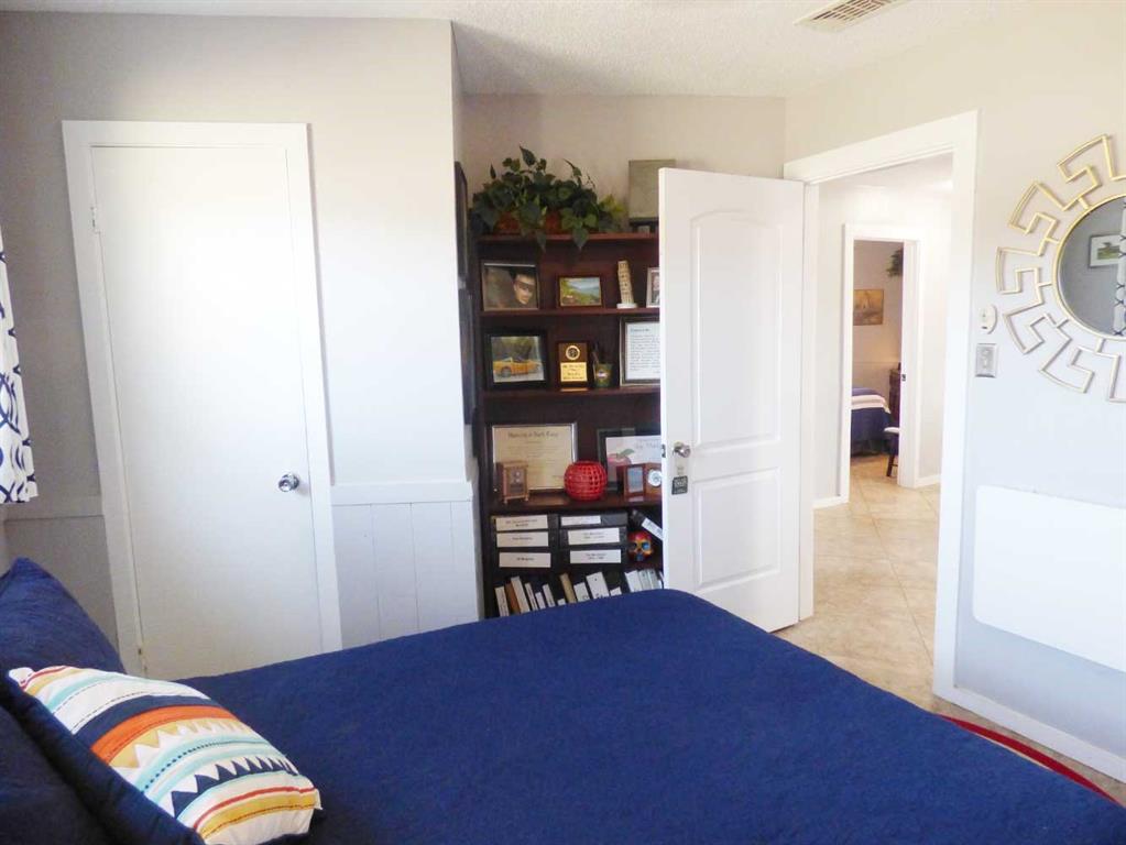 149 Bay Roc Lane Runaway Bay, TX 76426 - Photo 17 of 35 a bedroom with a bed and a bookshelf with wooden floor