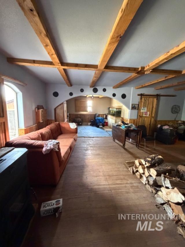 105 3rd Street Grand View, ID 83624 - Photo 13 of 19 Open-concept living space featuring wood-finish flooring, exposed wood beam ceiling, and an arched entryway