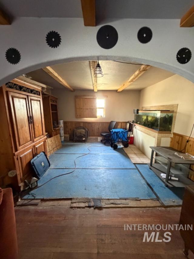105 3rd Street Grand View, ID 83624 - Photo 14 of 19 Arched doorway leading to a room with exposed ceiling beams and wood-finish wall paneling