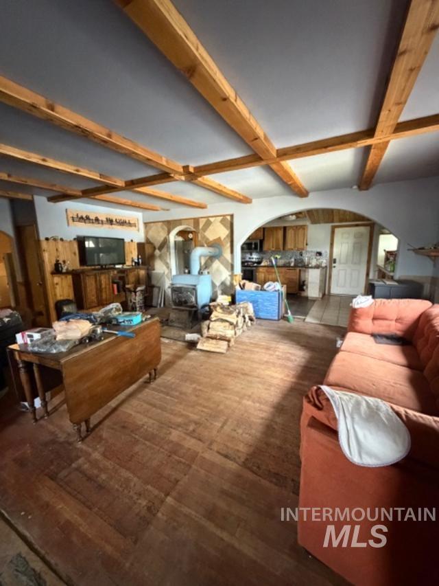 105 3rd Street Grand View, ID 83624 - Photo 15 of 19 Living area featuring wood-finish flooring, exposed ceiling beams, and a wood-burning stove