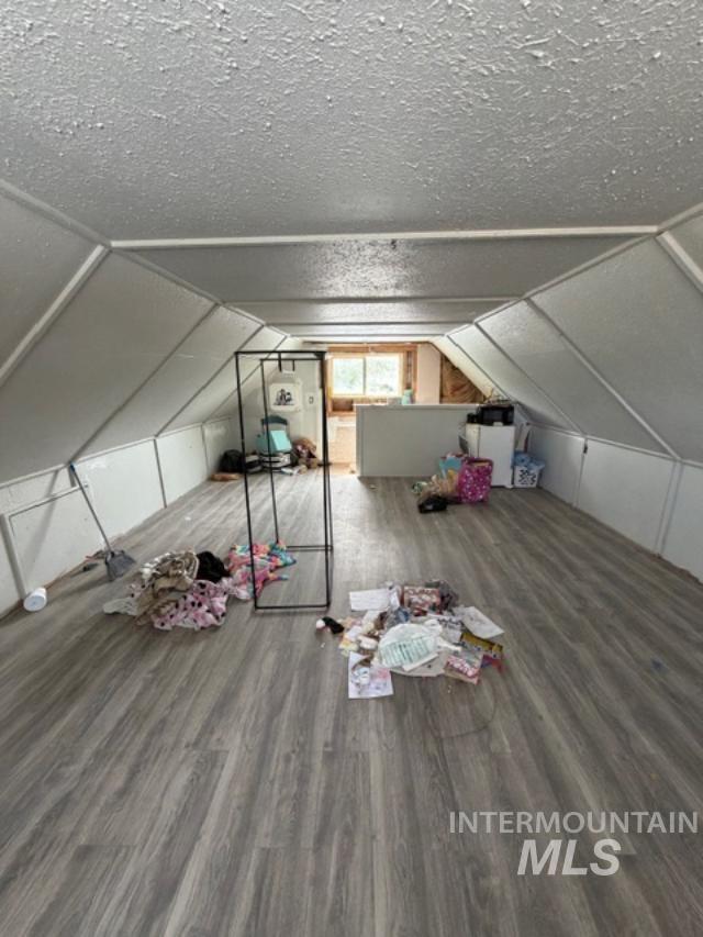 105 3rd Street Grand View, ID 83624 - Photo 17 of 19 Spacious attic room featuring wood-finish flooring, a textured ceiling, and an architectural vaulted design