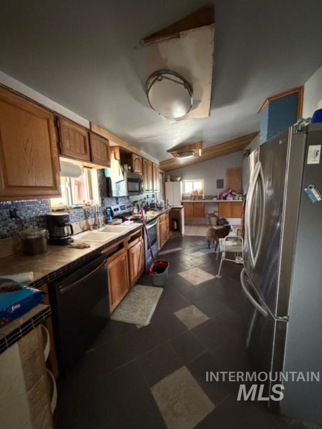 105 3rd Street Grand View, ID 83624 - Photo 10 of 19 Kitchen featuring wood cabinetry, a mosaic tile backsplash, black and light-toned floor tiling, and a stainless steel refrigerator