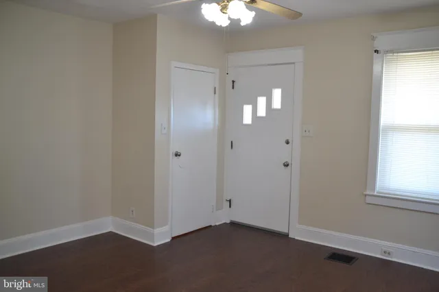 a view of an empty room with window and wooden floor