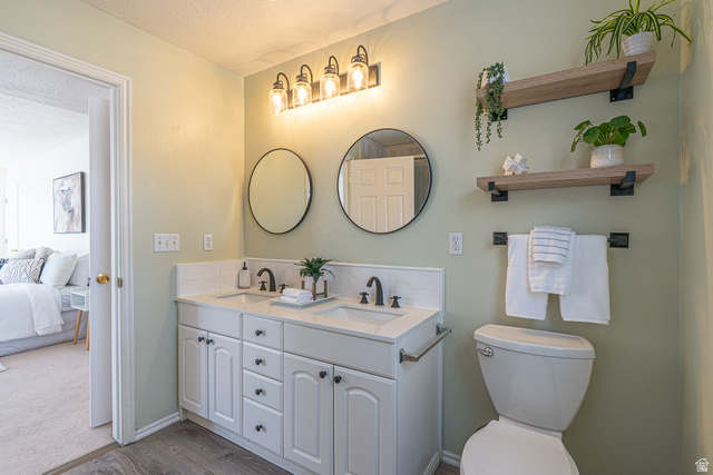 1045 Fox Farm Road Logan, UT 84321 - Photo 37 of 65 Ensuite bathroom featuring double vanity, a textured ceiling, and wood finished floors