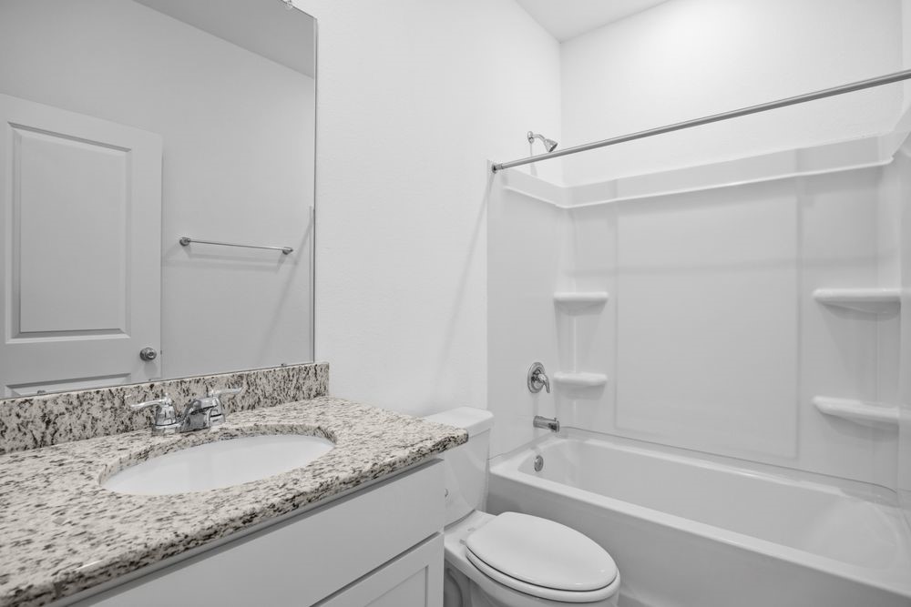 735 Willow Grove Lane Rosenberg, TX 77471 - Photo 17 of 26 a bathroom with a granite countertop sink a toilet and bathtub