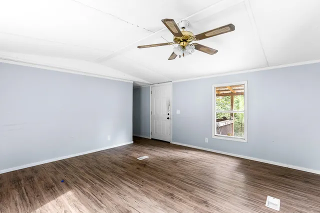 a view of a big room with wooden floor a ceiling fan and windows