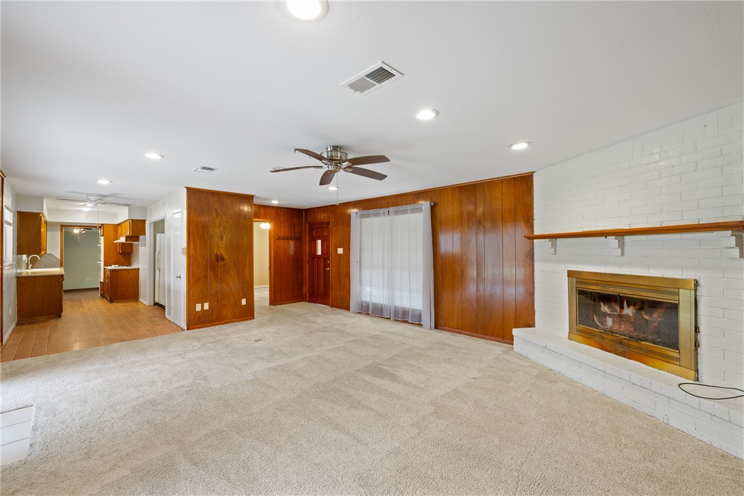 29 Dogwood Road Huntsville, TX 77320 - Photo 12 of 39 Unfurnished living room with light carpet, wooden walls, recessed lighting, a brick fireplace, and ceiling fan
