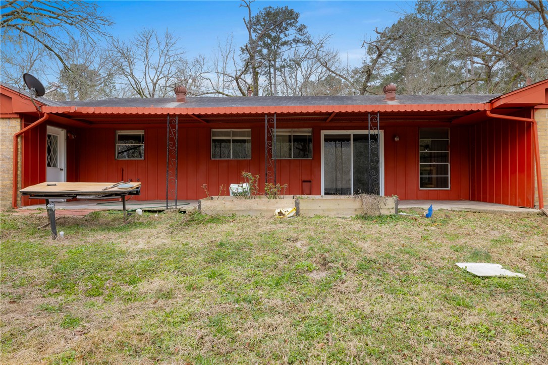29 Dogwood Road Huntsville, TX 77320 - Photo 6 of 39 Back of property featuring board and batten siding, a yard, a patio, and a metal roof