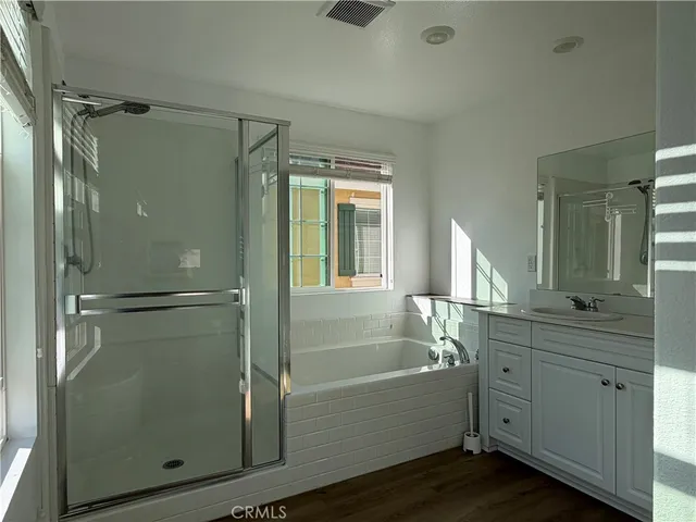 a bathroom with a bathtub shower sink vanity and mirror