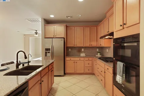 a kitchen with granite countertop a sink and refrigerator