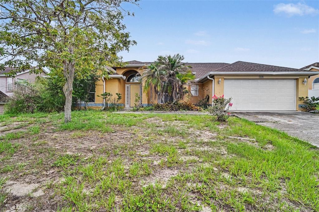 4716 Spaniel Street Orlando, FL 32818 - Photo 2 of 27 a front view of a house with a yard and garage