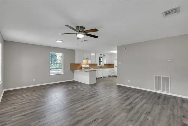 a view of an empty room with a window and wooden floor
