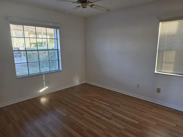 an empty room with wooden floor and windows