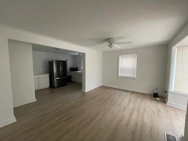 an empty room with wooden floor chandelier and windows