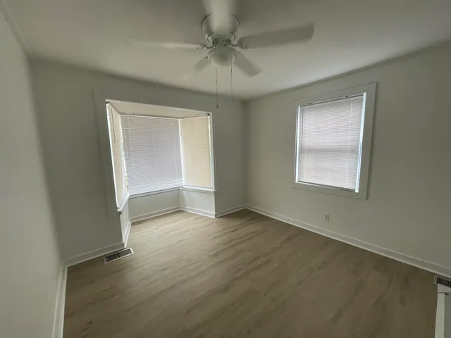 an empty room with a window and a ceiling fan