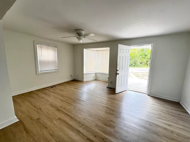 a view of an empty room with wooden floor and a window