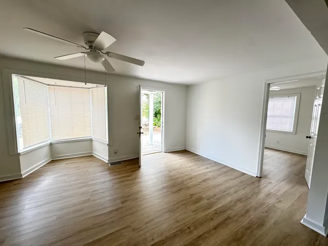 an empty room with wooden floor and windows